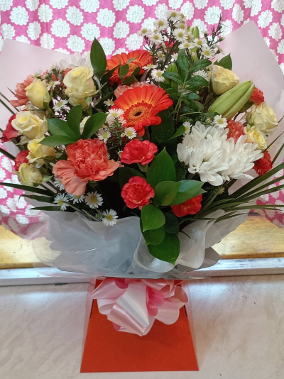 Sunlit Peach - A bright bouquet in warm coral, peach and creamy white tones, complemented by fresh greenery and delicate white accents.